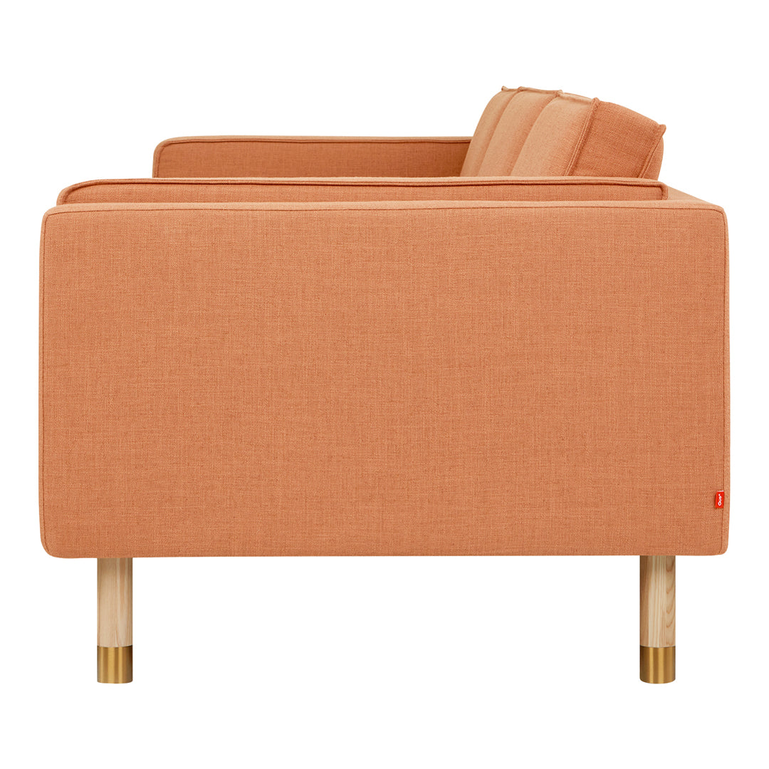 "Coral orange fabric sofa with clean lines and natural wood legs, adding a modern touch to any space."