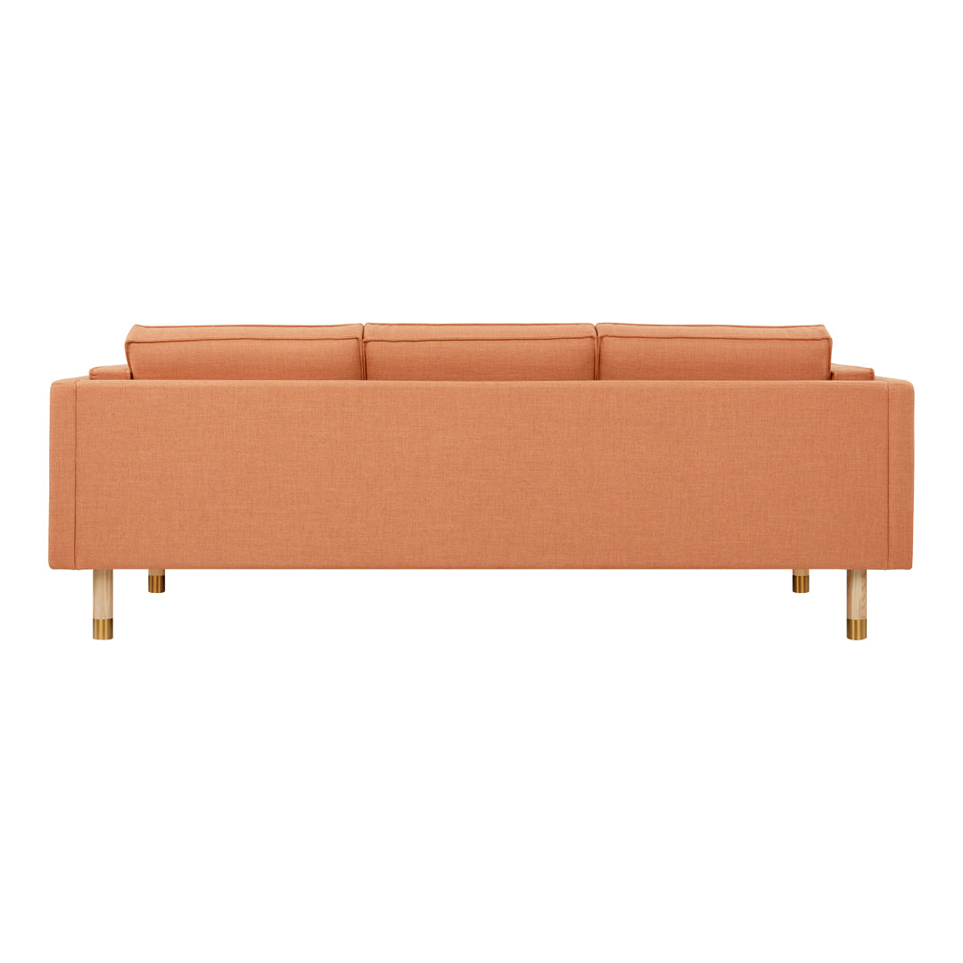 Peach-colored sofa with a sleek design, featuring a simple pattern and golden legs for a modern touch.