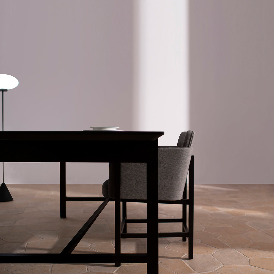 Stylish black wooden table with a sleek gray chair on a warm-toned, patterned floor.