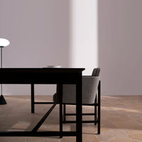 Stylish black wooden table with a sleek gray chair on a warm-toned, patterned floor.