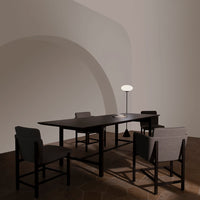 Modern dark wood dining table with grey upholstered chairs, featuring clean lines and a minimalist design.