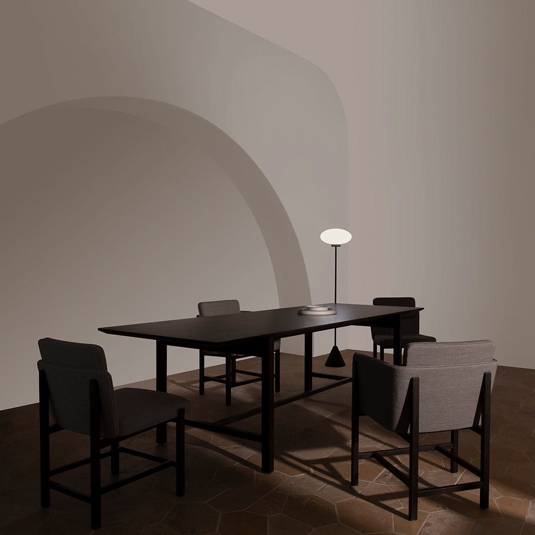 Modern furniture set in earthy tones with a sleek black table and light gray chairs, featuring minimalist design elements.