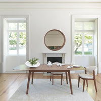 Modern wooden dining table with a warm brown finish, surrounded by neutral-colored chairs and a soft, light rug.