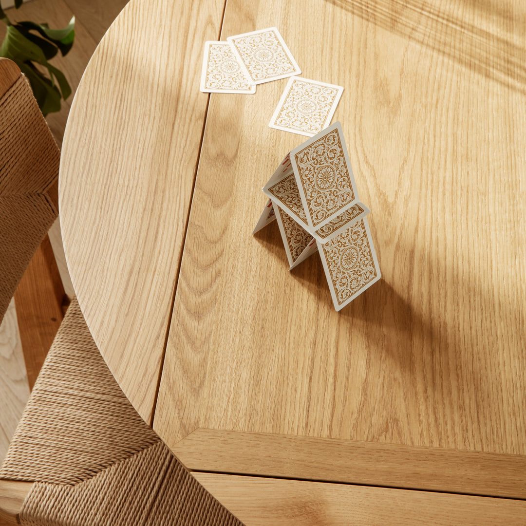 "Stack of ornate white playing cards on a warm wooden table with a natural finish."