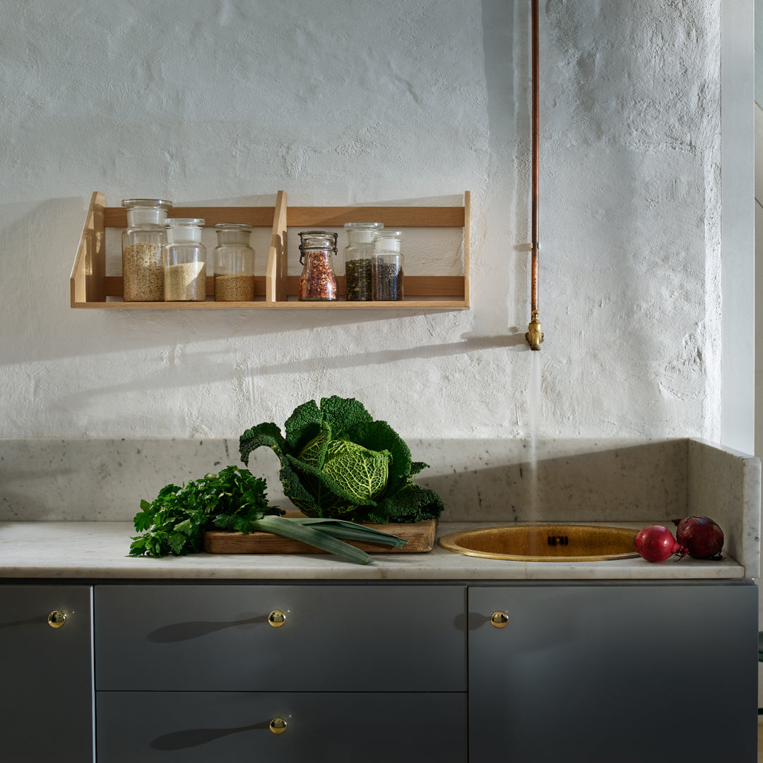 "Modern kitchen with gray cabinets, wooden spice rack, fresh green vegetables, and natural textures."