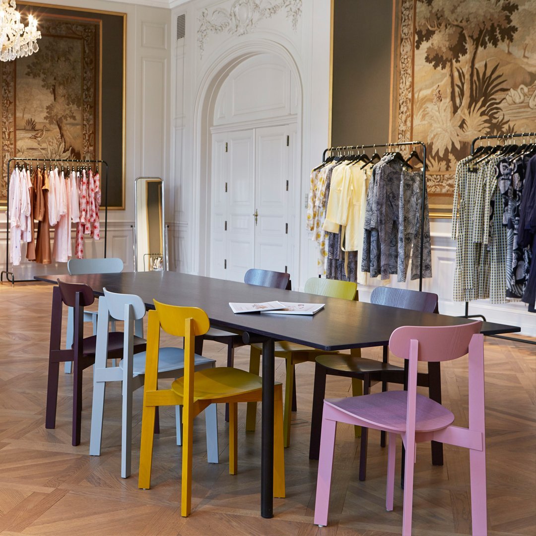 Colorful chairs in soft pastels and bold hues arranged around a sleek black table in an elegant setting.