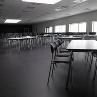 Modern black chairs and light gray tables on sleek black flooring in a spacious, bright room.