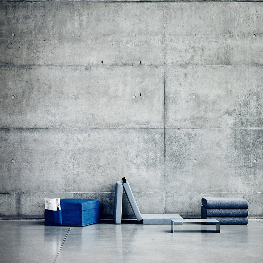 Blue and gray yoga mats and blocks arranged against a textured concrete wall, showcasing a modern minimalist design.