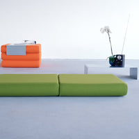 Vibrant green and orange padded seating with sleek modern design and white table in minimalist space.