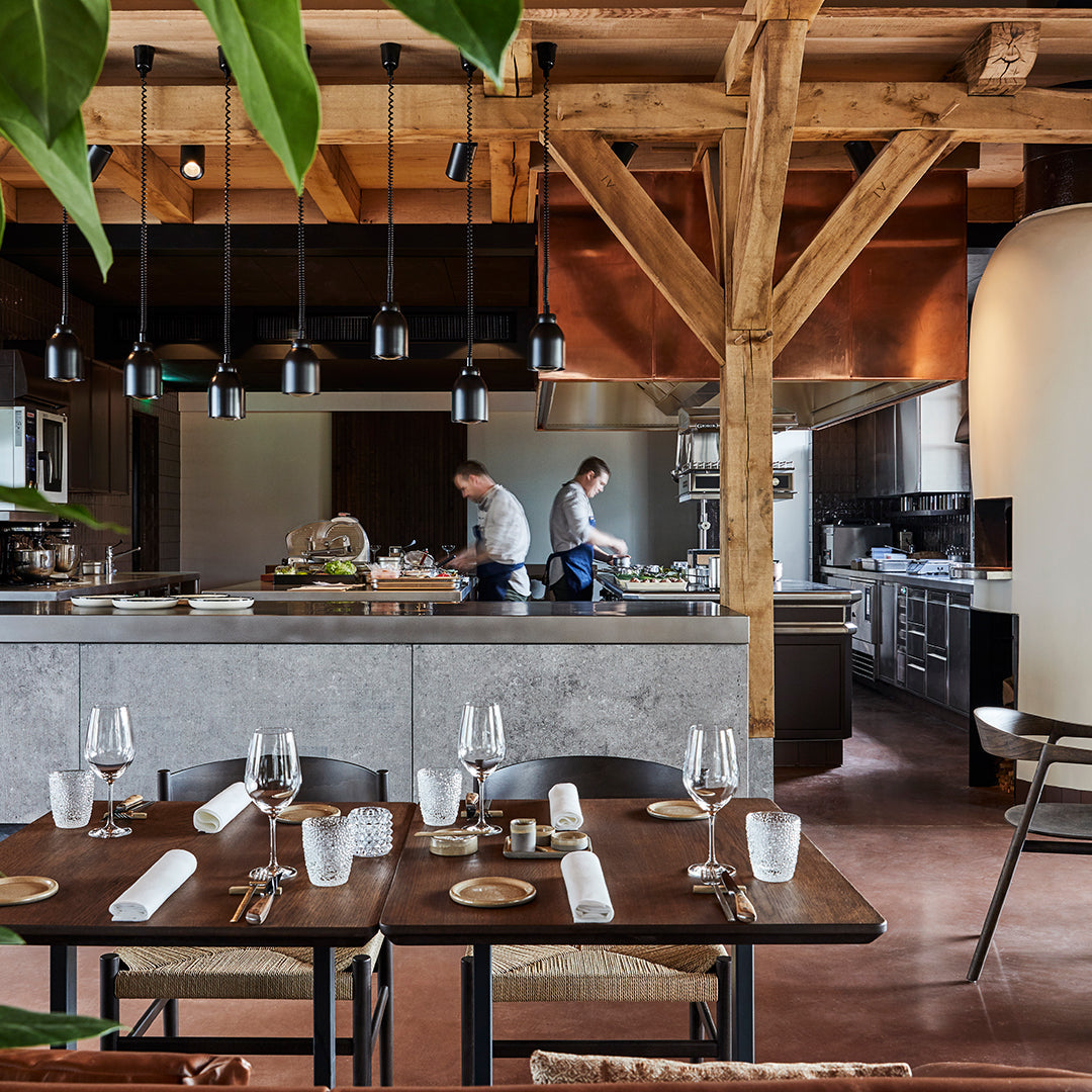 Modern kitchen interior with wood beams, copper accents, and sleek gray surfaces in a warm, inviting color palette.