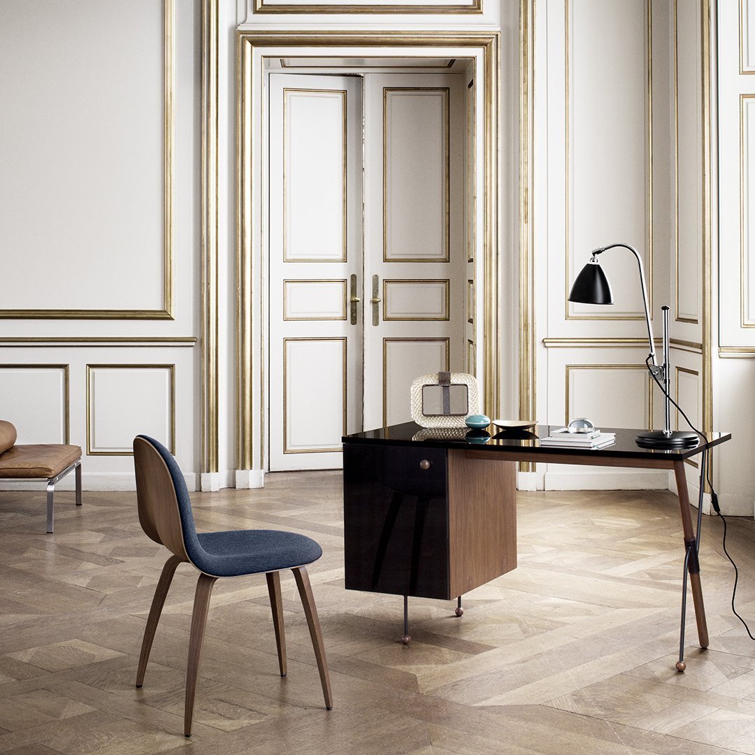 Mid-century modern desk in dark wood with contrasting navy chair, featuring elegant gold trim and light oak flooring.