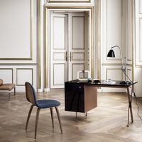 Mid-century modern desk in dark wood with contrasting navy chair, featuring elegant gold trim and light oak flooring.