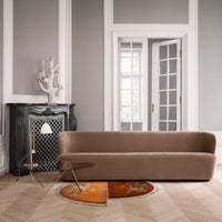 Sleek brown velvet sofa against gray walls, paired with an orange patterned rug and gold-accented side table.