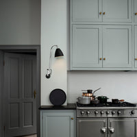Modern kitchen with soft grey cabinetry, black wall sconce, and stainless steel appliances, creating a sleek aesthetic.