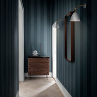 Navy blue and dark green striped walls complemented by a wooden dresser and gold accents. Elegant corridor decor.