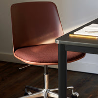 Brown ergonomic chair with a minimalist design and burgundy upholstered seat, complemented by a sleek silver base.