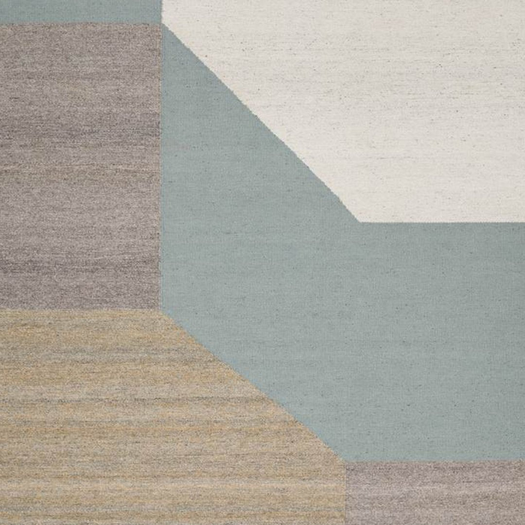 Geometric rug design featuring light gray, soft blue, beige, and cream tones with textured patterns.