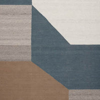 Geometric area rug featuring shades of blue, beige, and gray with a modern patchwork design.
