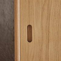 Close-up of light oak wood grain with a smooth finish, featuring a minimalist, rectangular handle cutout.