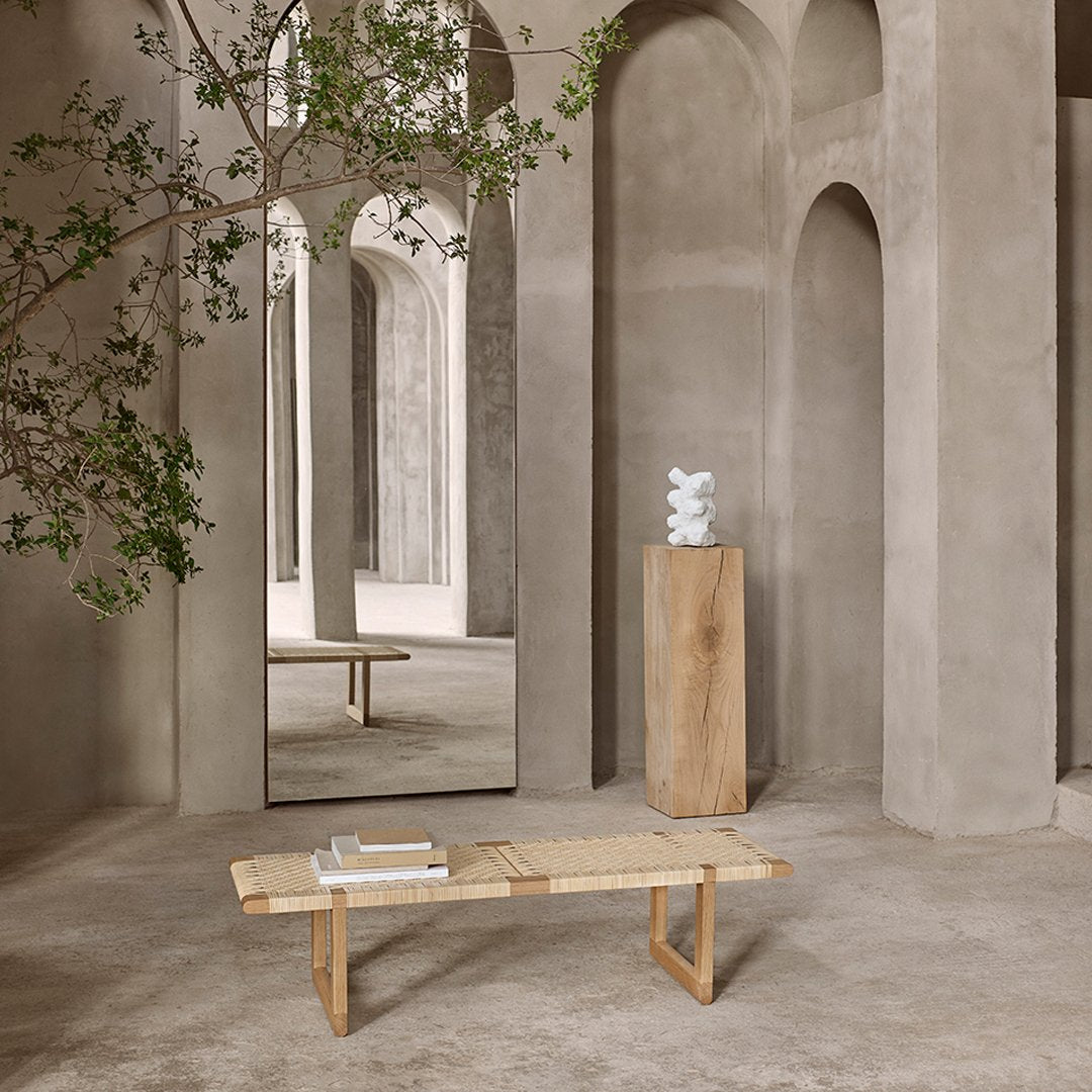 Natural wood bench with a light finish, set against muted gray walls and minimalistic decor. Elegant and serene.