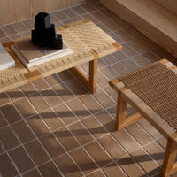 Natural wood coffee and side tables with woven patterns; warm beige tiles in a minimalist interior.