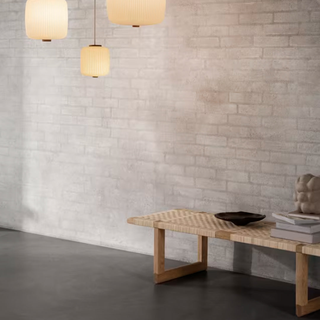 Modern space with gray brick wall, sleek black floor, and light wood textured bench; soft beige pendant lights.
