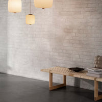 Modern space with gray brick wall, sleek black floor, and light wood textured bench; soft beige pendant lights.