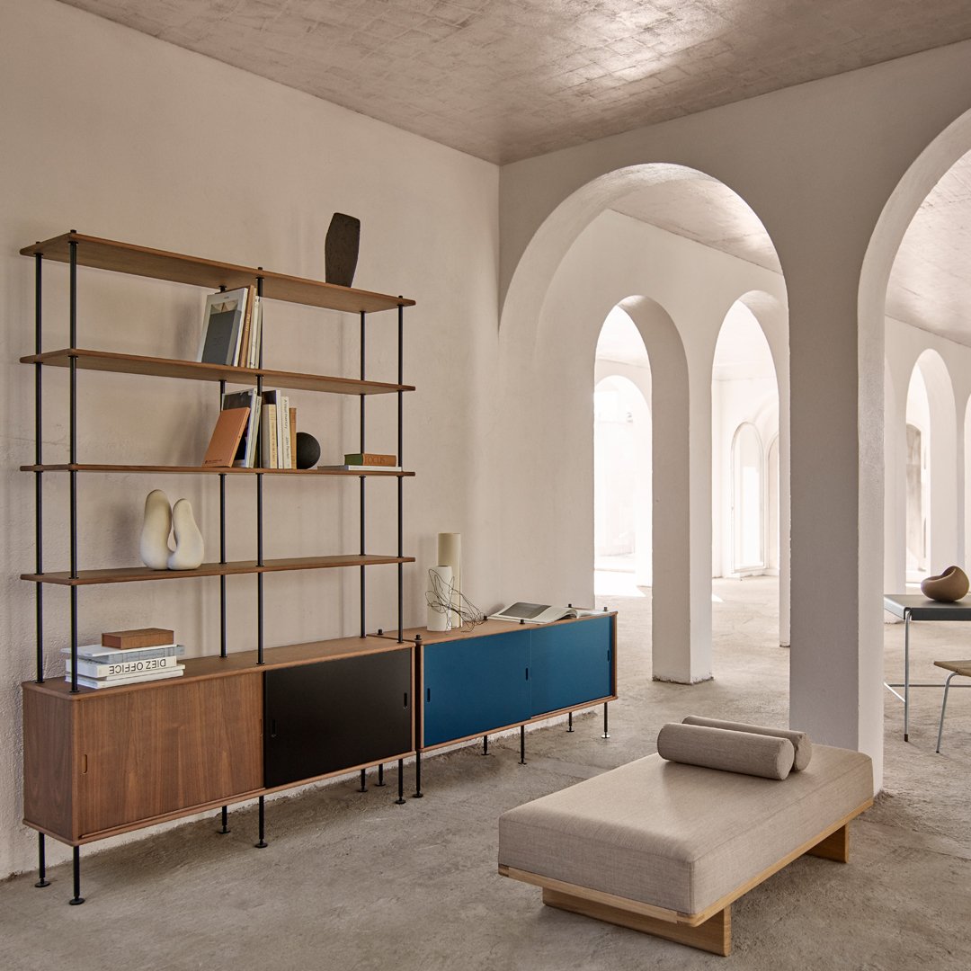 Modern wood shelving unit with dark brown, black, and vibrant blue finishes in a soft, neutral-toned room.