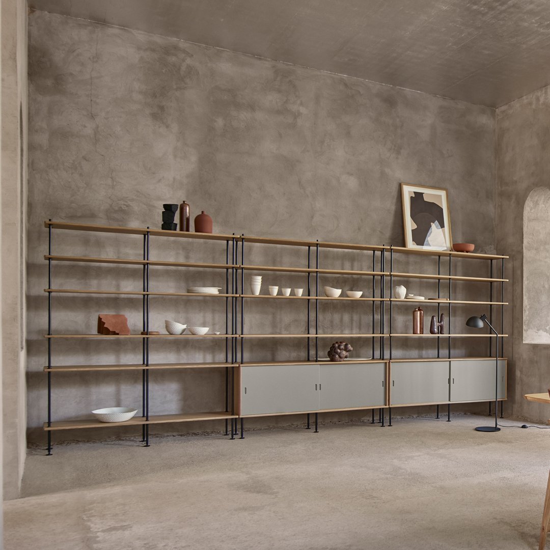 Modern shelving unit with a mix of natural wood, sleek gray, and earthy tones. Minimalist design with open and closed storage.