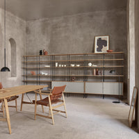 Modern wooden shelving unit with black metal accents, set against a textured gray wall and beige carpet.
