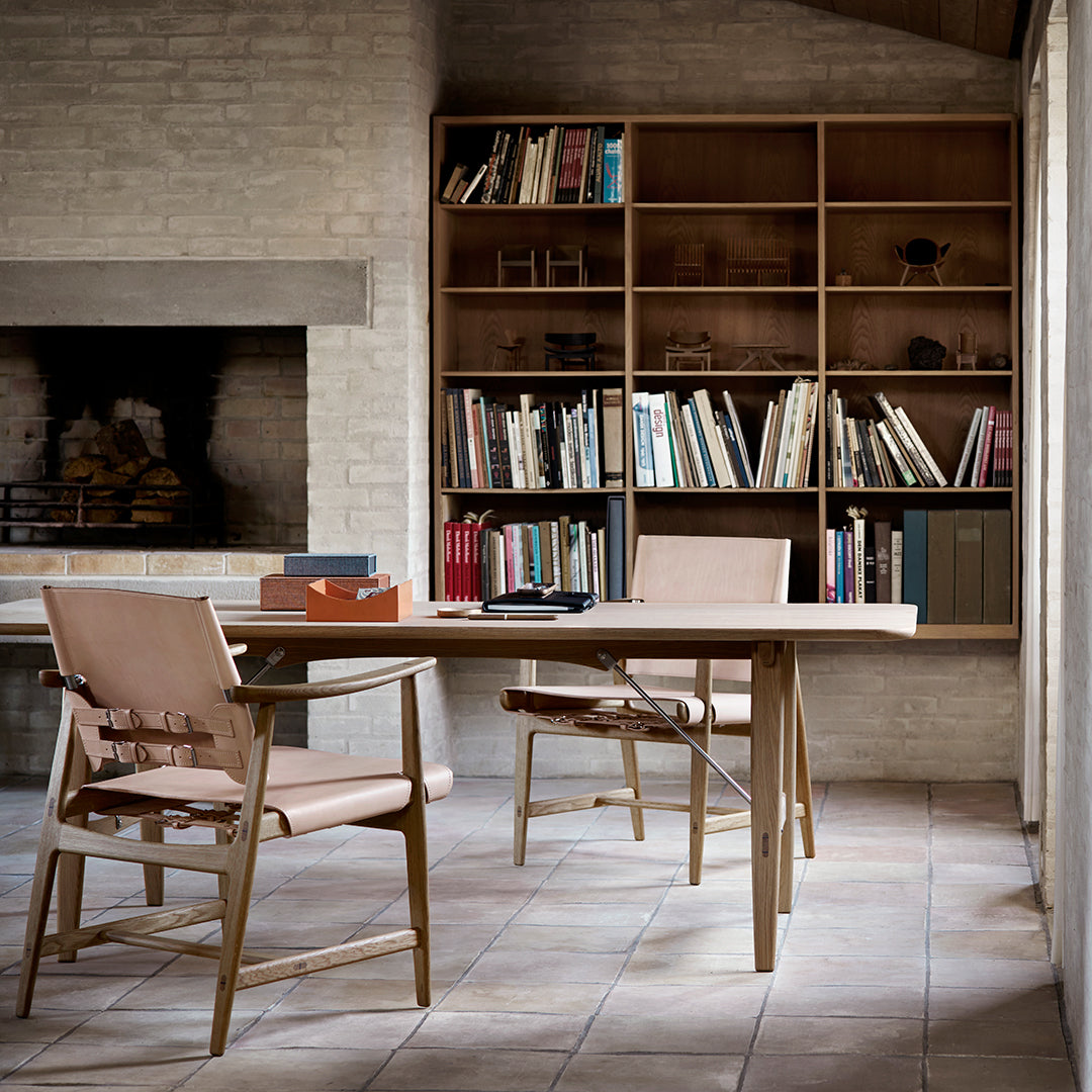 Light wood table with minimalist design, beige chairs, and natural tones, set in a warm, neutral-toned room.