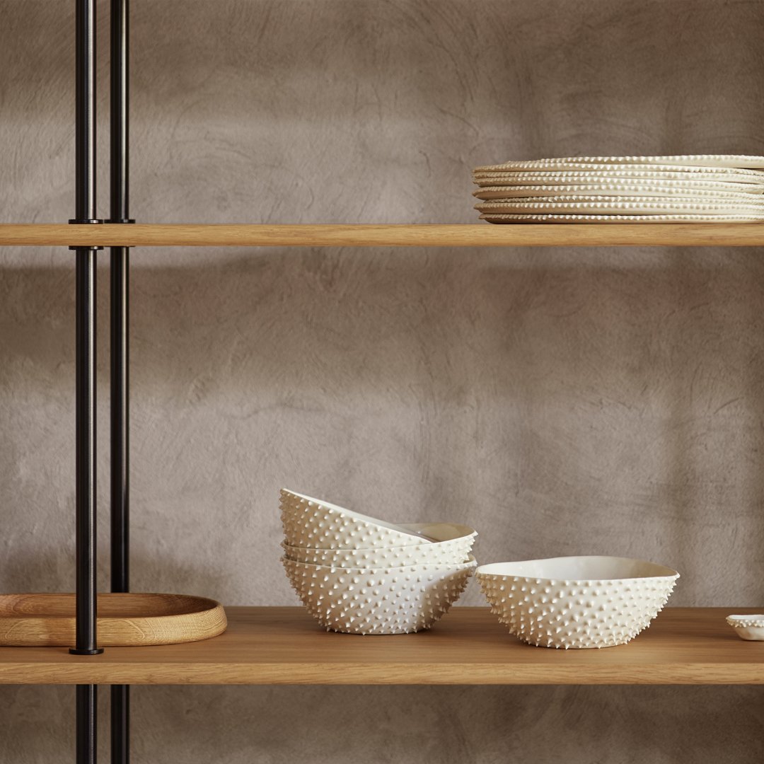 White ceramic bowls with textured patterns on wooden shelves against a neutral, textured wall background.
