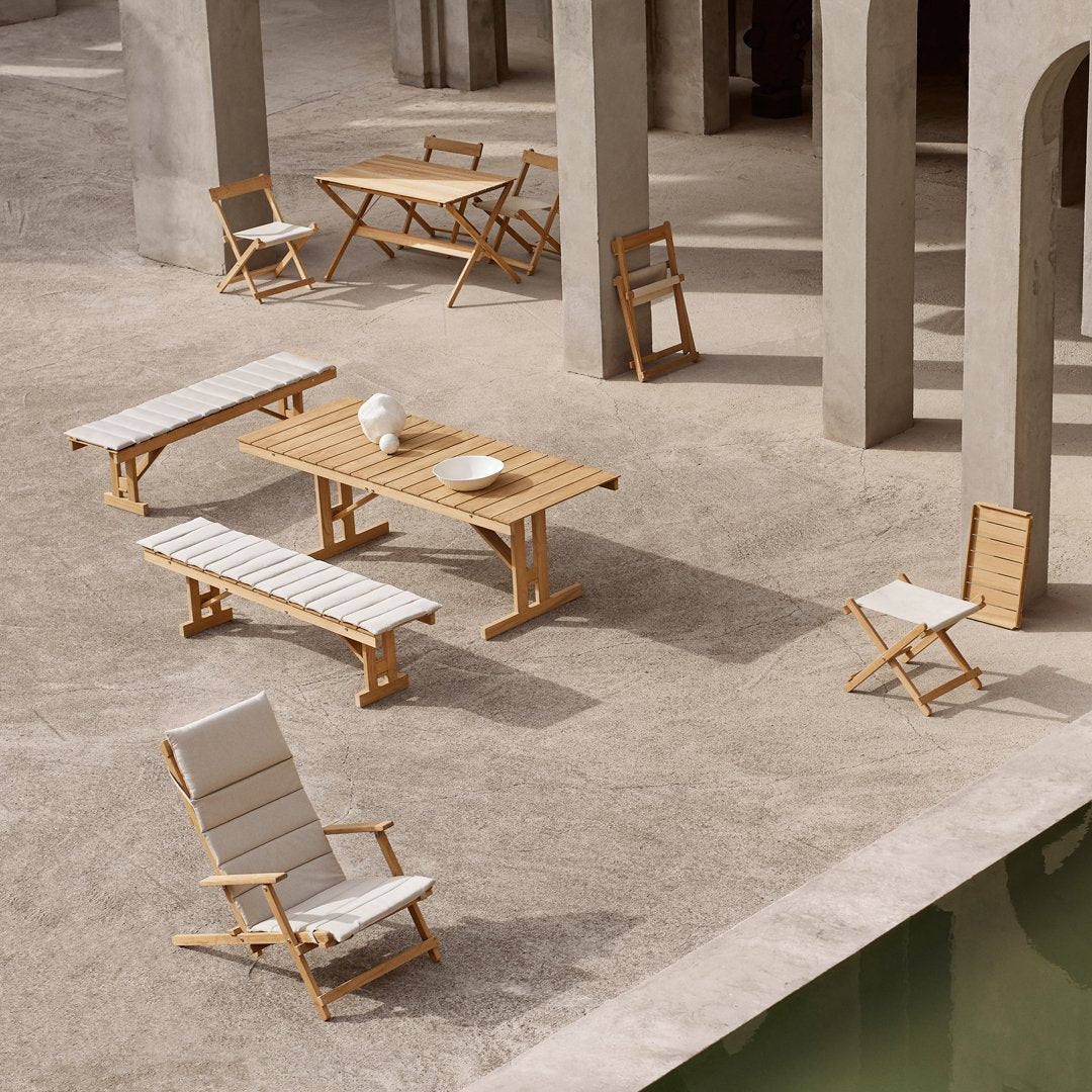Natural wood hues with white slatted patterns in outdoor furniture set against a minimalist stone backdrop.