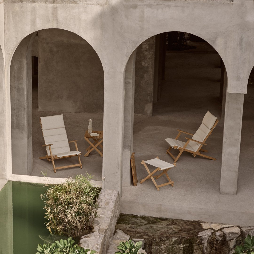 "Neutral-toned folding chairs with cream fabric and wooden frames, set against a minimalist concrete backdrop."