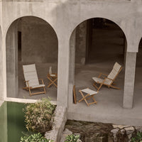 "Neutral-toned folding chairs with cream fabric and wooden frames, set against a minimalist concrete backdrop."