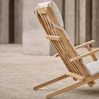 Natural wood reclining chair with beige cushions, showcasing minimalist design and textured fabric patterns.
