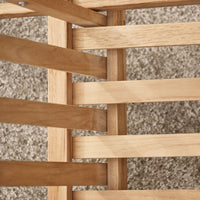 Close-up of light wood slats with a natural finish, arranged in a crisscross pattern over a soft, beige carpet.