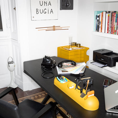 Stylish black desk with vibrant yellow organizer and accessories, featuring clean lines and a modern aesthetic.