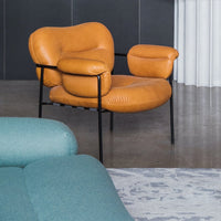 Orange leather chair with soft curves, paired with a light teal sofa against a textured gray rug.