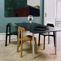 Modern dining table with sleek black surface, complemented by minimalist black, wood, and gray chairs in a stylish interior.