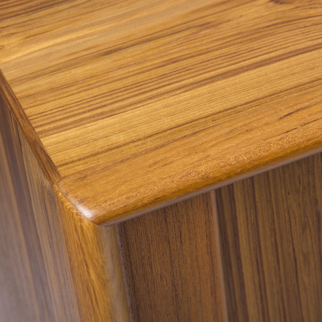 Close-up of a warm golden-brown wood surface showcasing fine, natural stripes and a smooth finish.