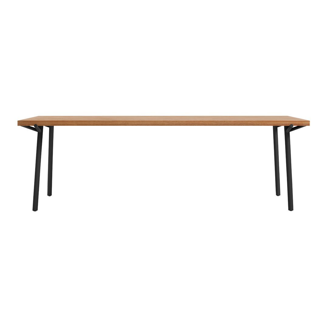 Long wooden table with a warm oak finish and sleek black metal legs, offering a modern, minimalist design.