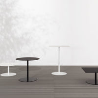 Modern minimalist tables in black and white with sleek circular and rectangular designs on a wooden floor.