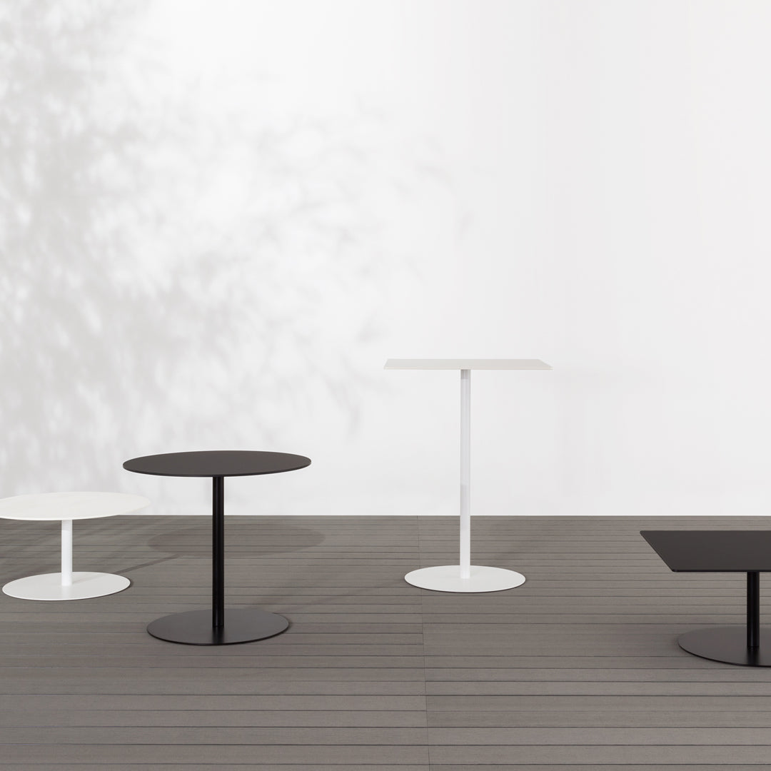 "Four modern tables in black and white with sleek round and rectangular tops, set against a minimalist background."