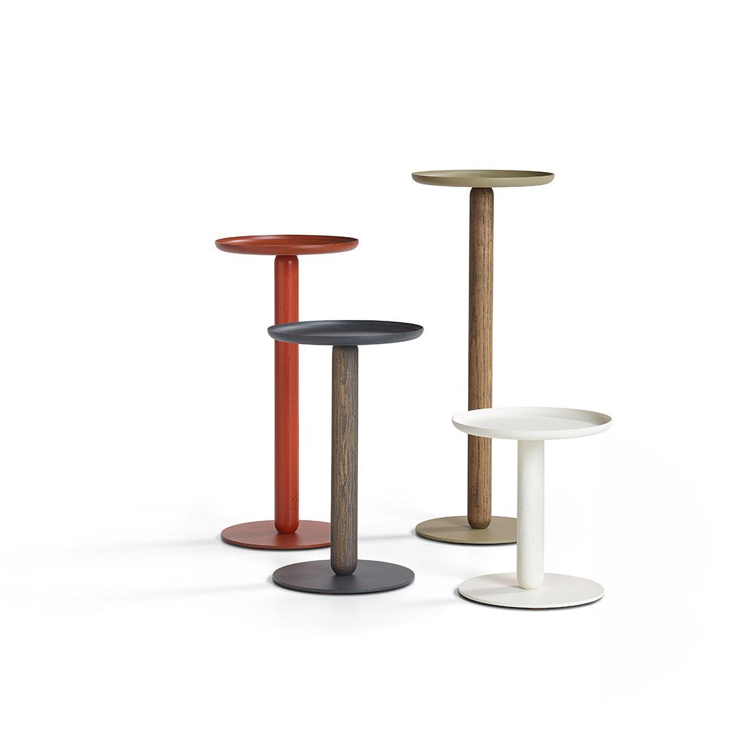 Four modern side tables featuring red, olive green, black, and white finishes with sleek circular tops.