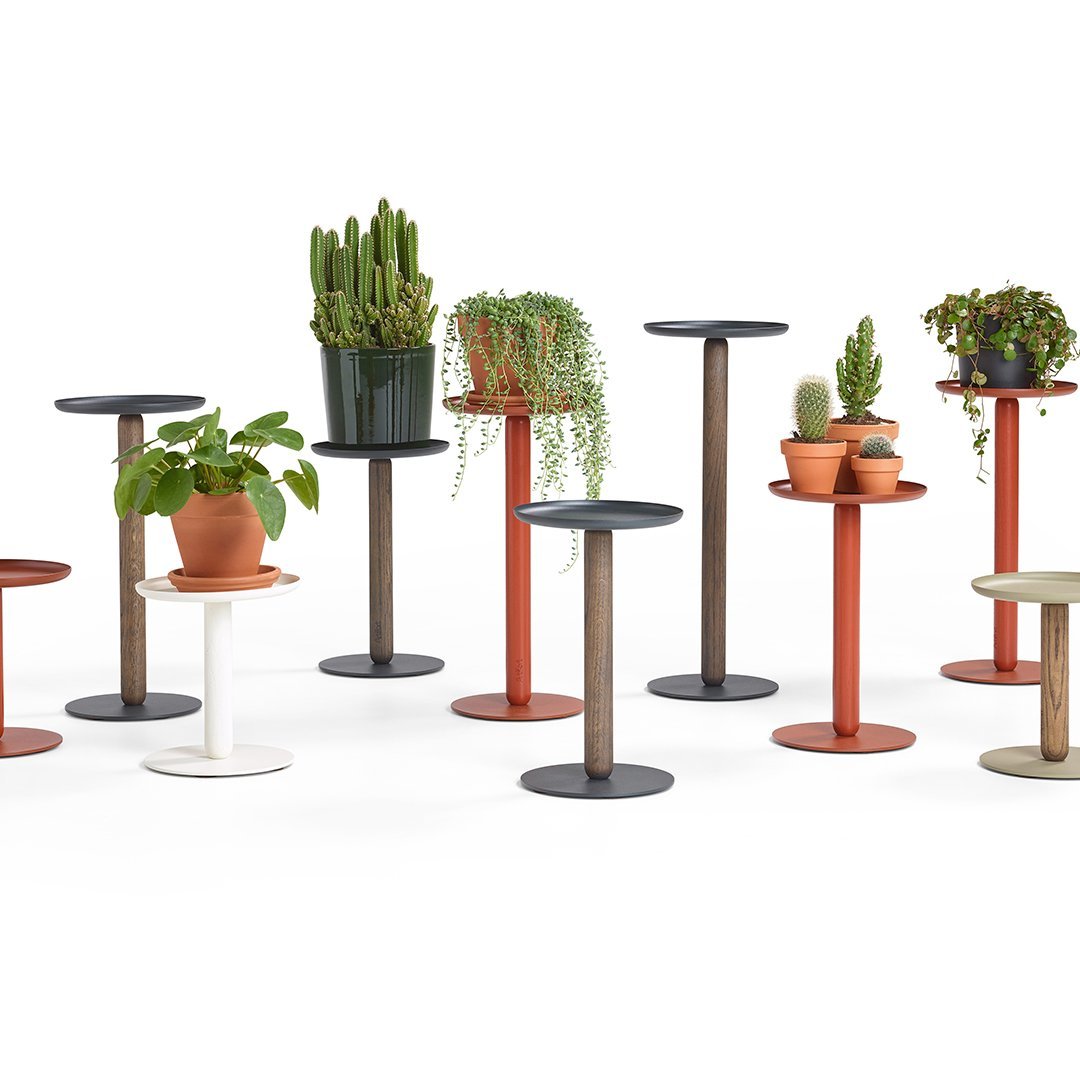 Various plant stands in black, white, red, and natural wood tones, featuring smooth finishes and modern designs.