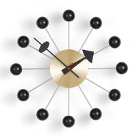 Mid-century modern wall clock featuring a gold face, black accents, and red hands against a white background.