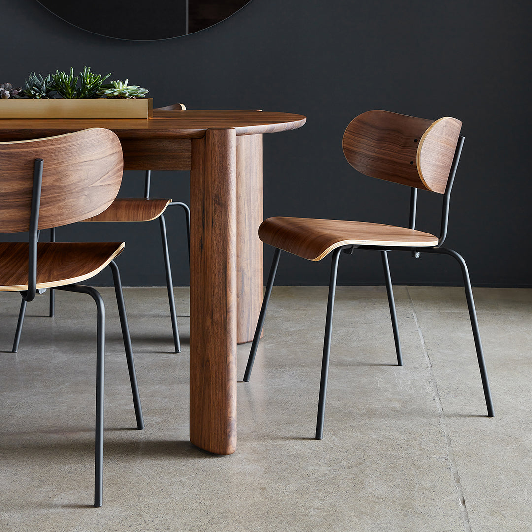 Wooden dining chairs with warm walnut finish and sleek black metal legs, set against a minimalist background.