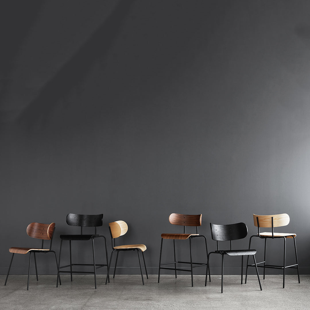 Set of modern chairs featuring warm wood tones and sleek black metal accents against a dark gray backdrop.