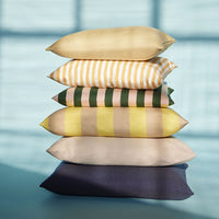 Stacked pillows in yellow, green, and navy with striped and solid patterns. Perfect for adding color to any space.